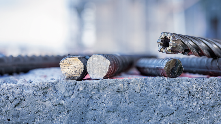 切割钢筋和旋转钻头放在粗糙的混凝土表面上。