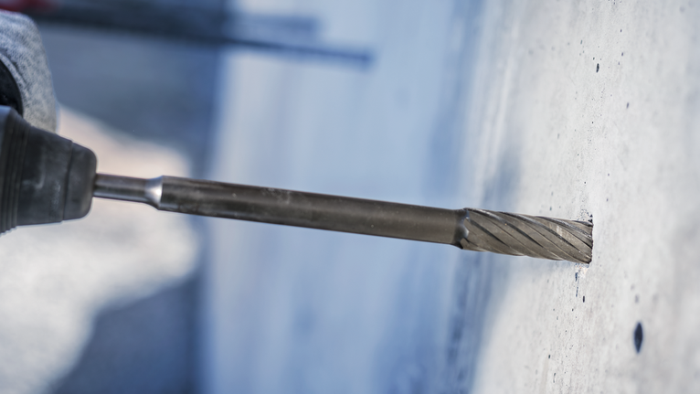 旋转锤钻在混凝土墙上钻出一个精确的孔。