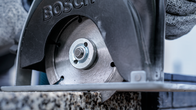 佩戴安全设备的人员用圆锯切割石头。