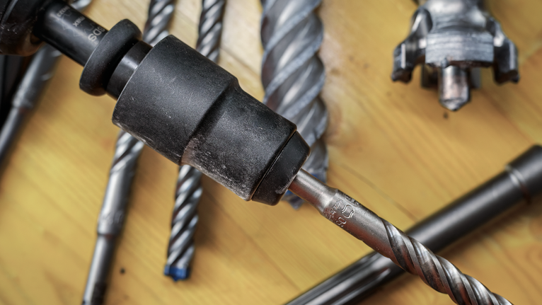 木质表面上各种金属钻头和钻夹头的特写。