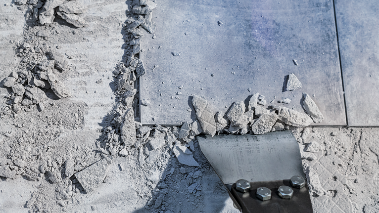 凿刀将瓷砖从布满灰尘的地板上铲掉。