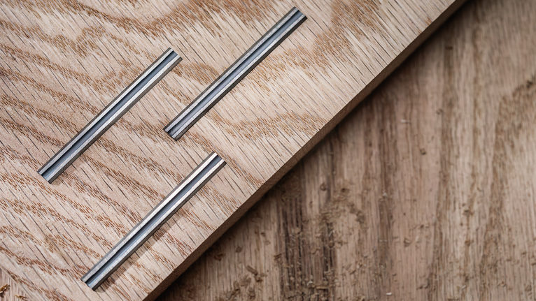 三个凹槽金属镶嵌物嵌入浅色木板中。