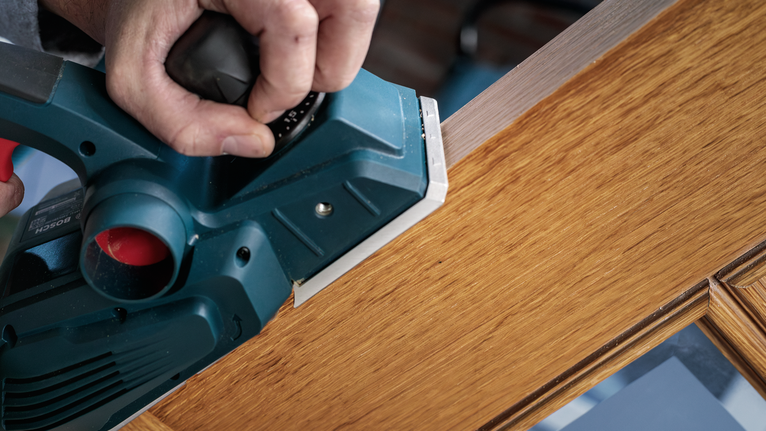 电动刨床正在打磨木门的边缘。.