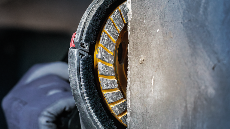 一名佩戴安全设备的人员使用金刚石锯片切割混凝土。