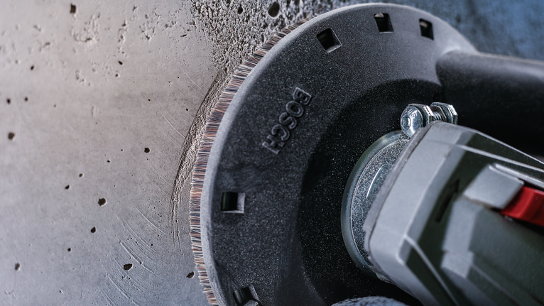 角磨机切割混凝土墙，边缘可见灰尘。.