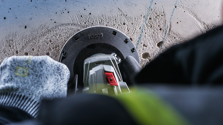 工人佩戴安全设备，使用电动工具钻入混凝土。.