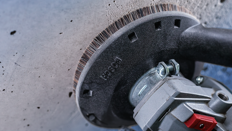 安装在电动工具上的钢丝杯刷可以清洁混凝土墙的表面。.