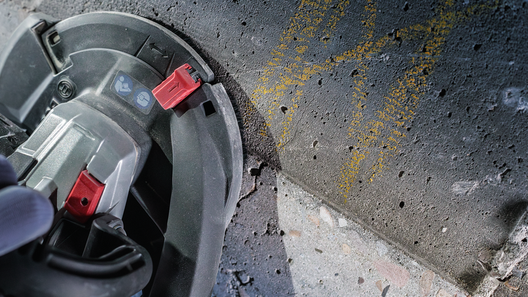 一名佩戴安全设备的人员使用圆锯切割混凝土表面。