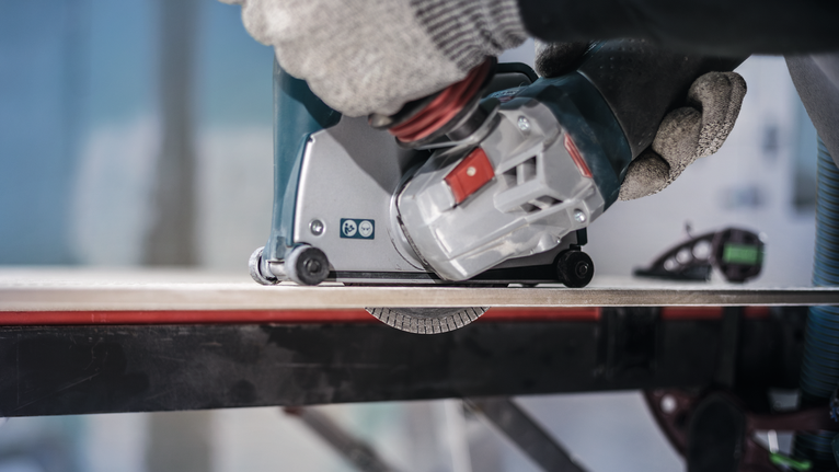 佩戴安全设备的人员操作电动工具切割瓷砖。