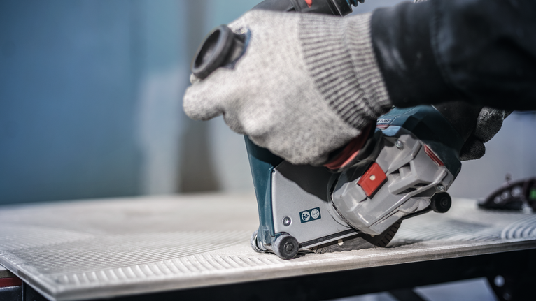 佩戴安全设备的人员使用电动工具切割瓷砖。