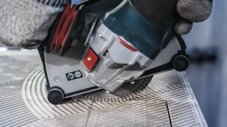 佩戴安全设备的人员使用圆锯切割瓷砖。