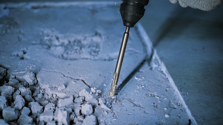 一名佩戴安全设备的人员使用旋转锤破碎混凝土。