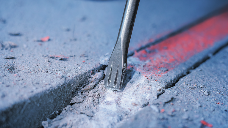 凿子钻头沿着标记线破碎混凝土。