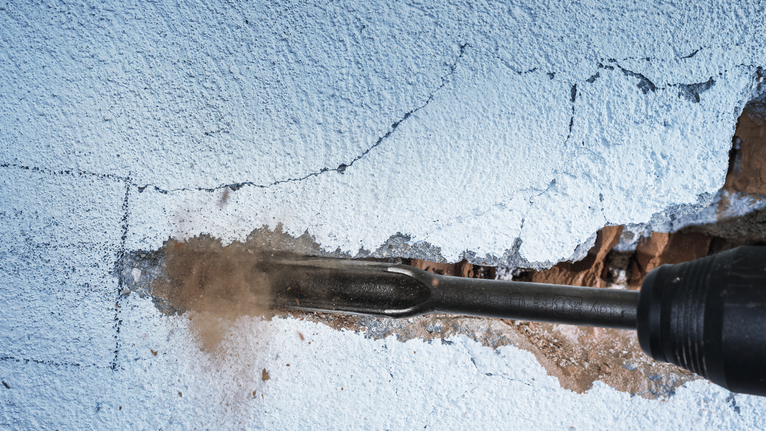 旋转锤在抹灰的墙上凿出凹槽。.