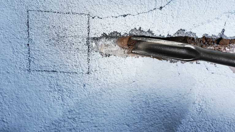 凿子工具在混凝土墙上形成凹槽。