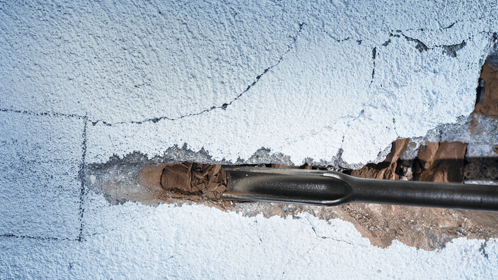 凿子工具凿破墙上的灰泥。