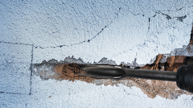 用凿子拆除有裂缝的混凝土墙。