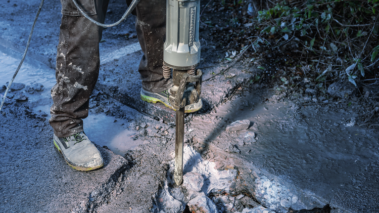 佩戴安全设备的人员使用拆除工具拆除路面。