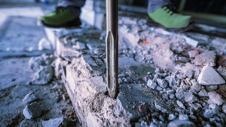 佩戴安全设备的人员使用拆除工具破碎混凝土。