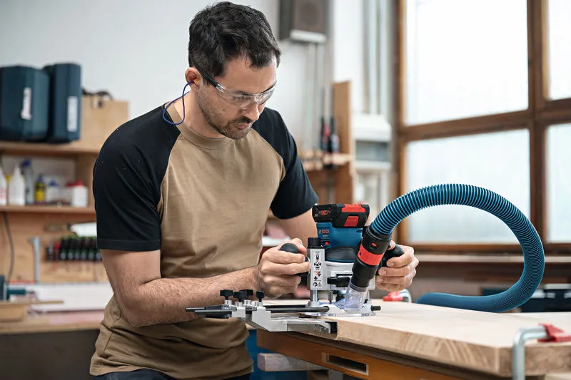 一名佩戴安全设备的人员在木板上操作无绳掌上路由器。.