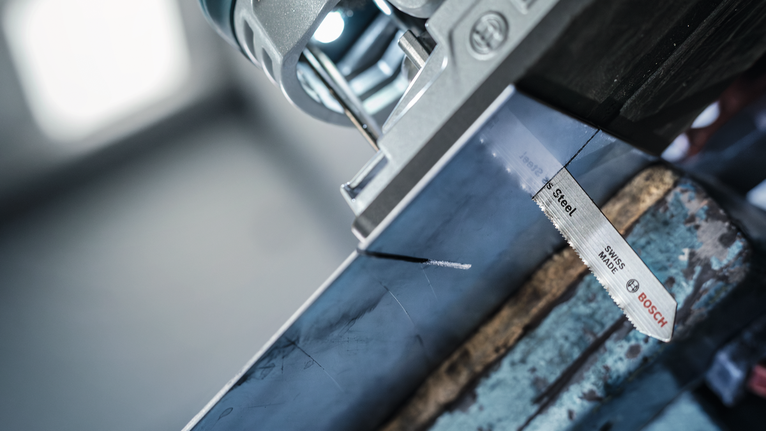 车间里，拼图锯切割着标记的金属梁。