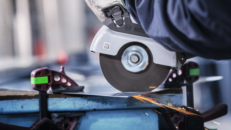 佩戴安全设备的人用圆锯切割金属板，产生火花。