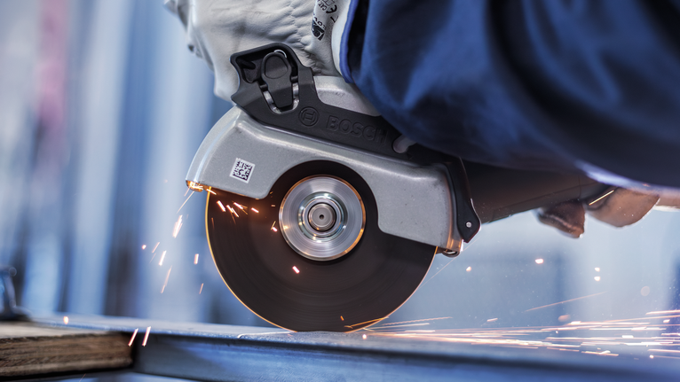 佩戴安全设备的人用圆锯切割金属，产生火花。