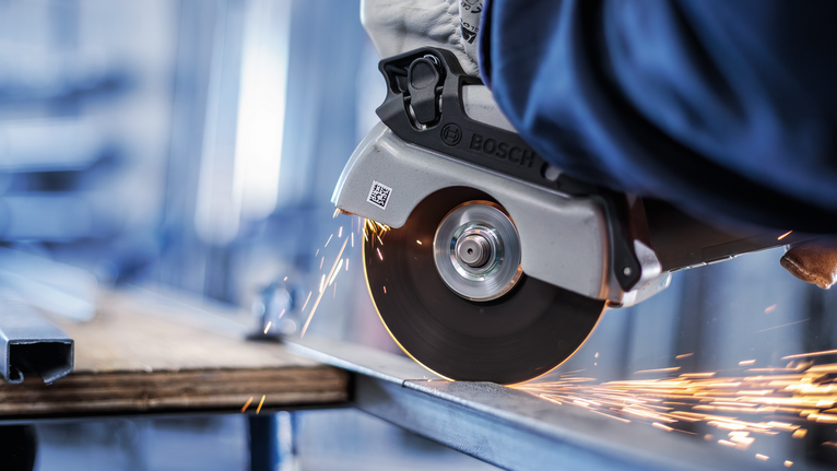 佩戴安全设备的人用圆锯切割金属，产生火花。