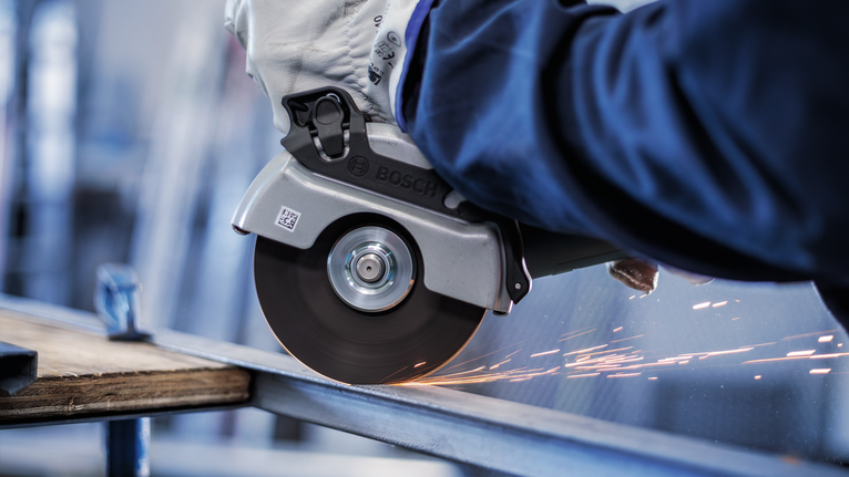 佩戴安全设备的人员使用角磨机切割金属梁。