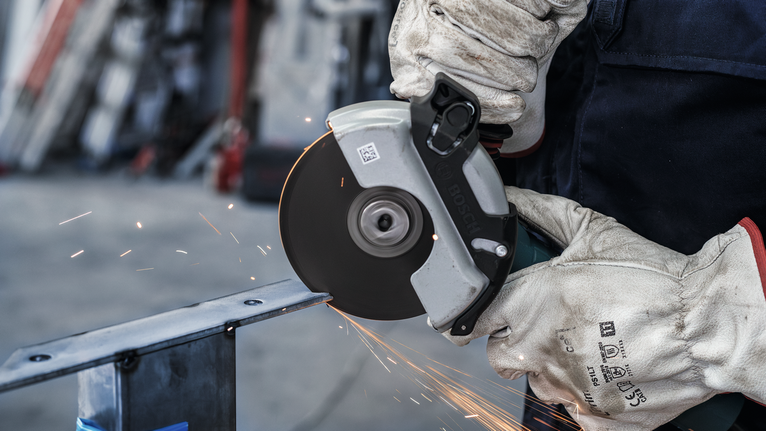 一名佩戴安全设备的人用圆锯切割金属，产生火花。