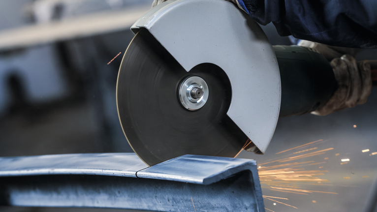 一名佩戴安全设备的人员正在使用大型角磨机切割金属。