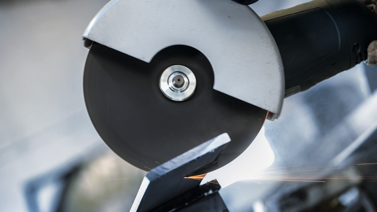 一名佩戴安全设备的人使用角磨机切割金属。