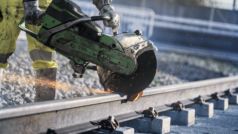 一名佩戴安全设备的人用大型电锯切割金属栏杆。