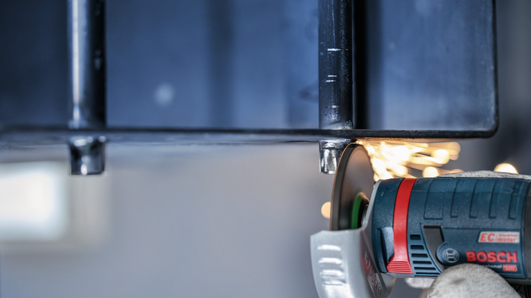 佩戴安全设备的人研磨金属，产生火花。