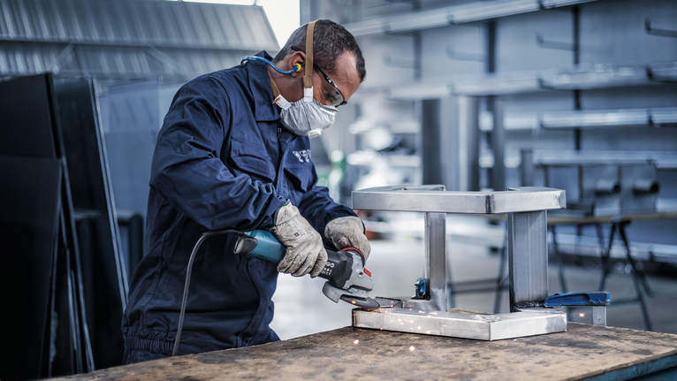 佩戴安全设备的人研磨金属框架，产生火花。