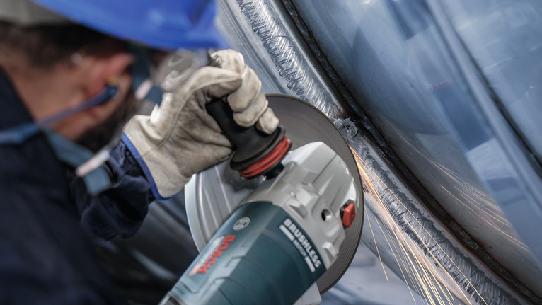 佩戴安全设备的人研磨金属，产生火花。