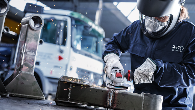 佩戴安全设备的人研磨金属，产生火花。