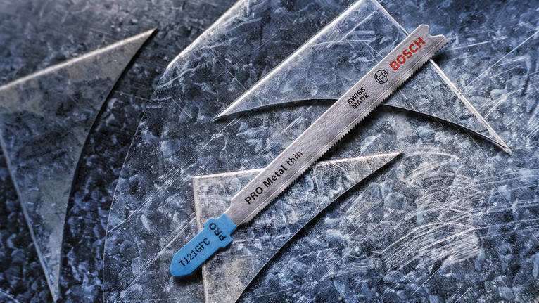 用于切割薄金属的曲线锯刀片放在有划痕的金属板上。