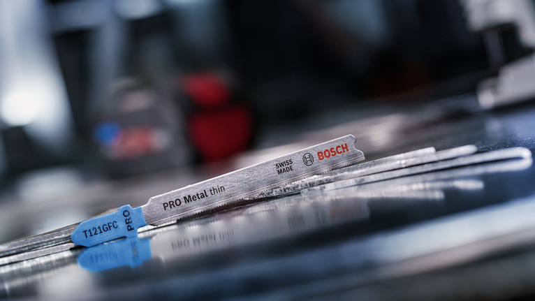 金属拼图刀片位于车间内反光的金属表面上。