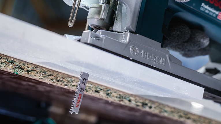 佩戴安全设备的人员使用拼图锯切割木板。