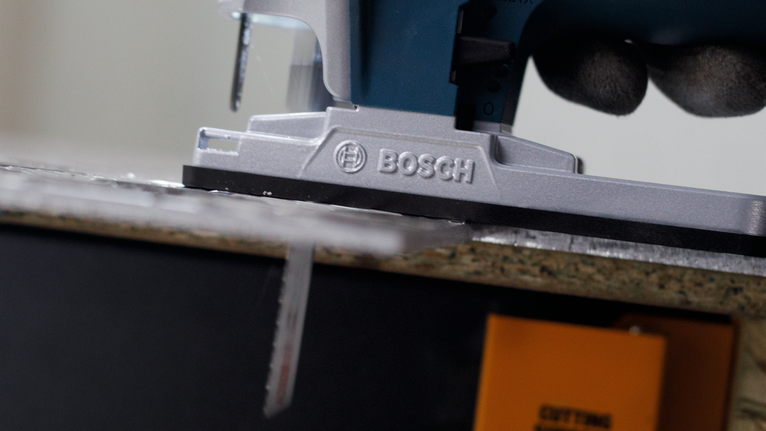 佩戴安全设备的人员引导拼图锯切割木板。