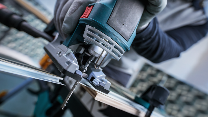 佩戴安全设备的人员用曲线锯切割木材。