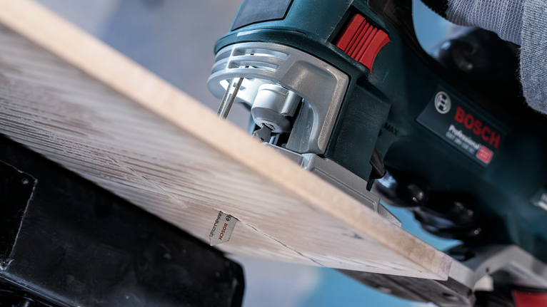 一个人引导拼图锯切开木板。