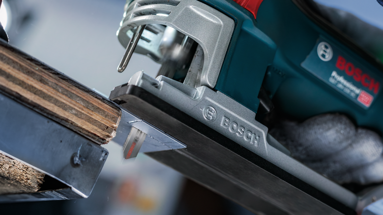 一名佩戴安全设备的人使用电动曲线锯切割木材。