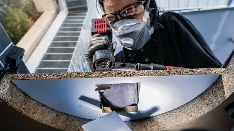 穿着安全设备的人员在木板上钻孔。