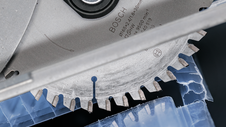 圆锯片切割蓝色塑料材料。