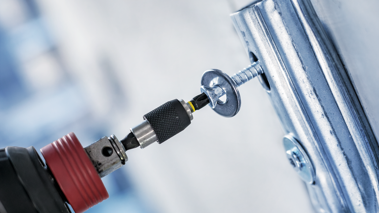 电动螺丝刀将螺丝拧入金属支架。