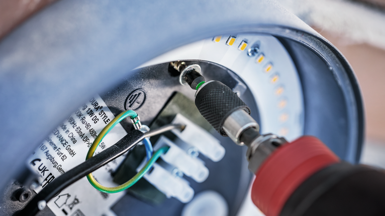 无绳螺丝刀拧紧圆形 LED 灯具内的螺丝。