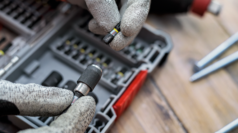 佩戴安全设备的人员从有序的盒子中选择一个螺丝刀头。