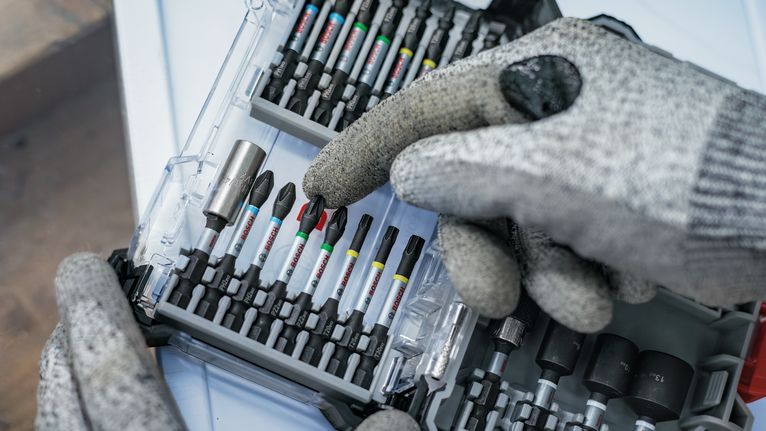 佩戴安全设备的人员从有序的工具箱中选择一个螺丝刀头。